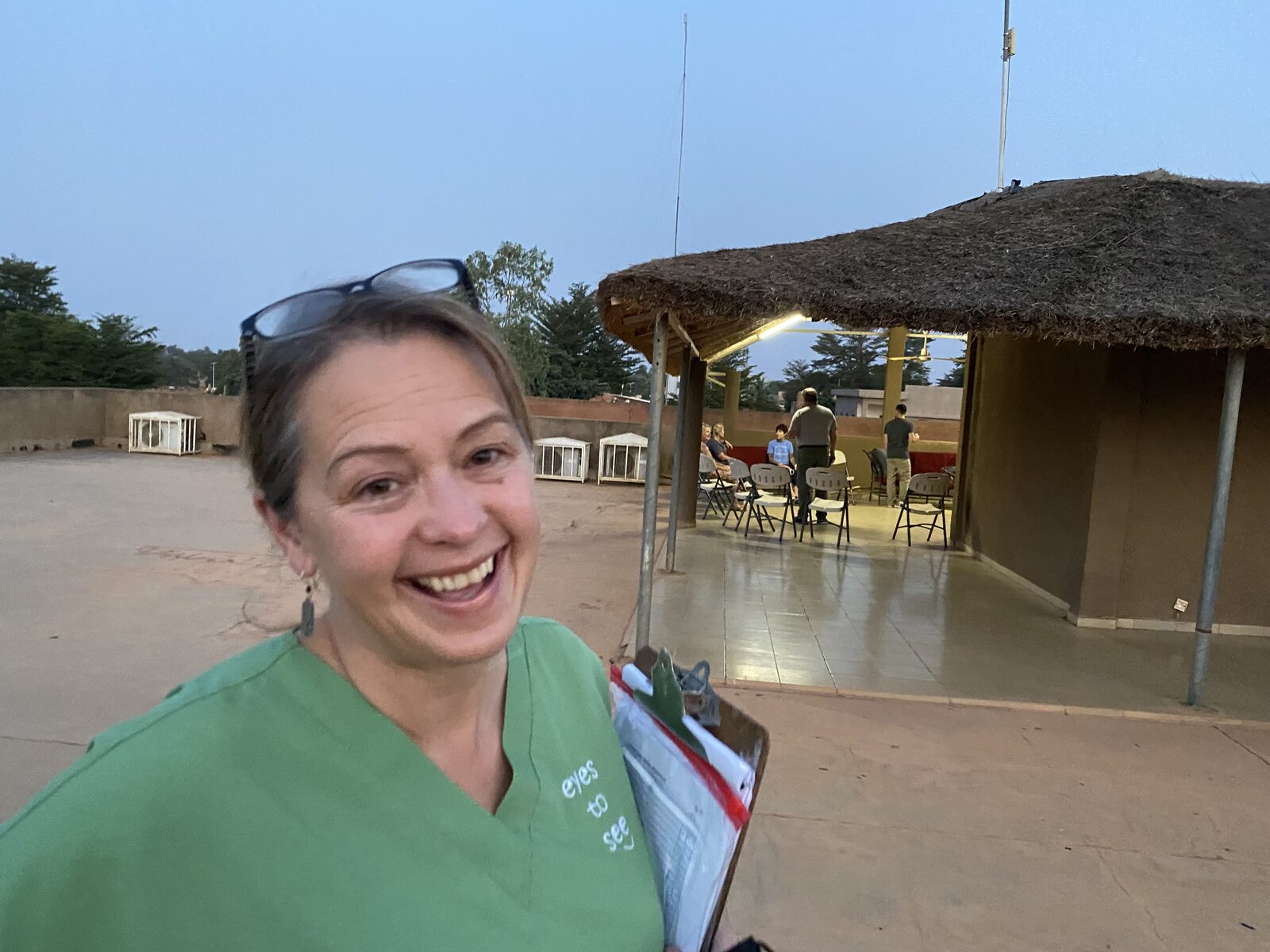 Dr. Lisa Vredevoogd on a medical mission trip in Africa, wearing Eyes to See scrubs and holding a clipboard